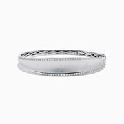 The 925 Sterling Silver Diamond Accented Bangle features a smooth, slightly curved center, two rows of sparkling stones along the edges, and a decorative lattice pattern inside.