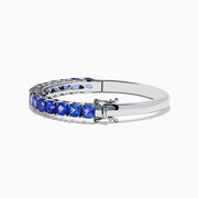 The Nahla Siri 925 Silver Tanzanite Bangle features a polished band set with sparkling blue gemstones, displayed on a white background.