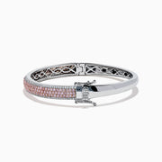 The 14K Two Tone Gold Pink and White Diamond Bangle features an intricate cutout design, accented by a central band with sparkling pink and white diamonds.