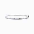 The 14K White Gold Diamond Spike Bangle showcases alternating pyramid studs and rows of sparkling diamonds on its sleek silver surface, set against a plain white background.