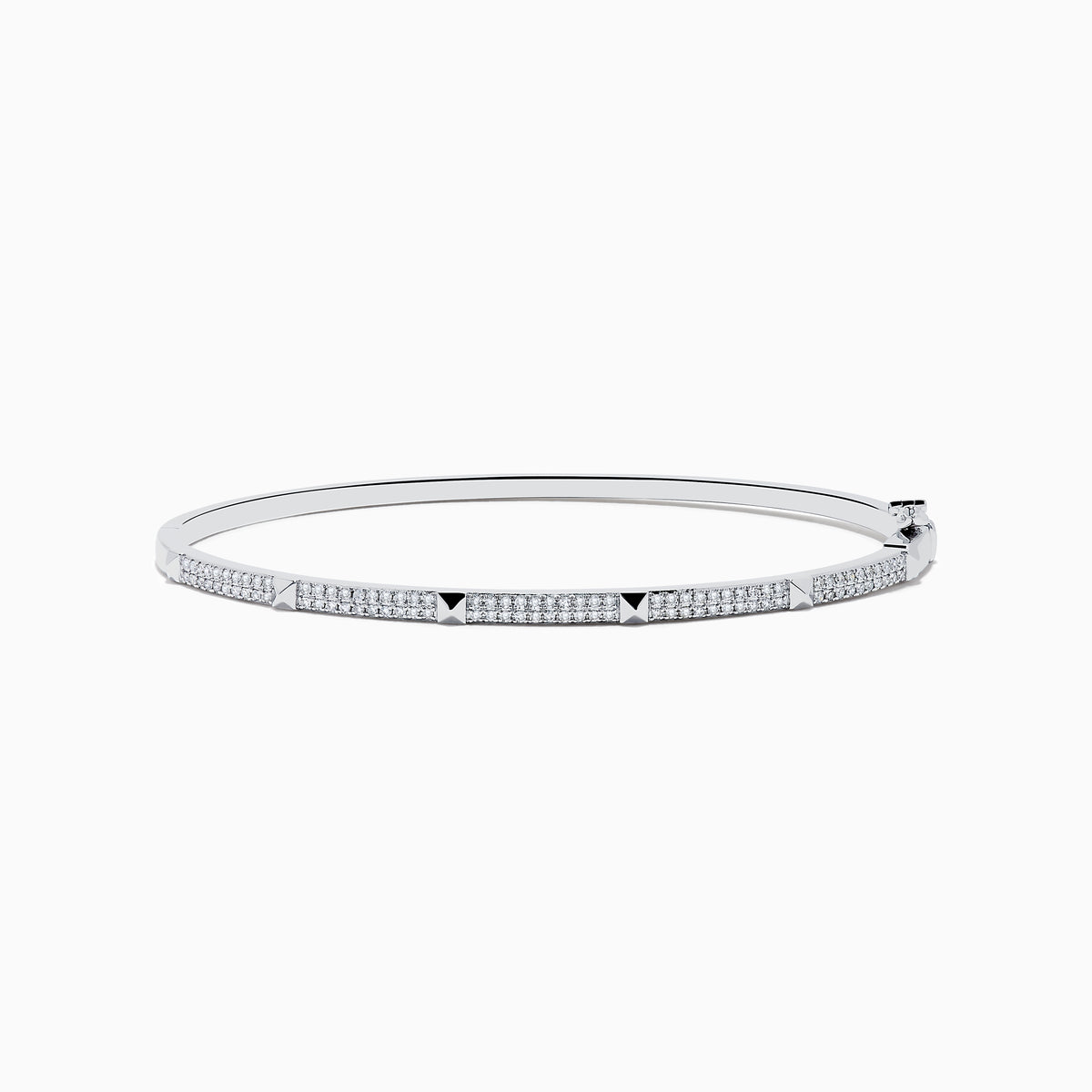 The 14K White Gold Diamond Spike Bangle showcases alternating pyramid studs and rows of sparkling diamonds on its sleek silver surface, set against a plain white background.