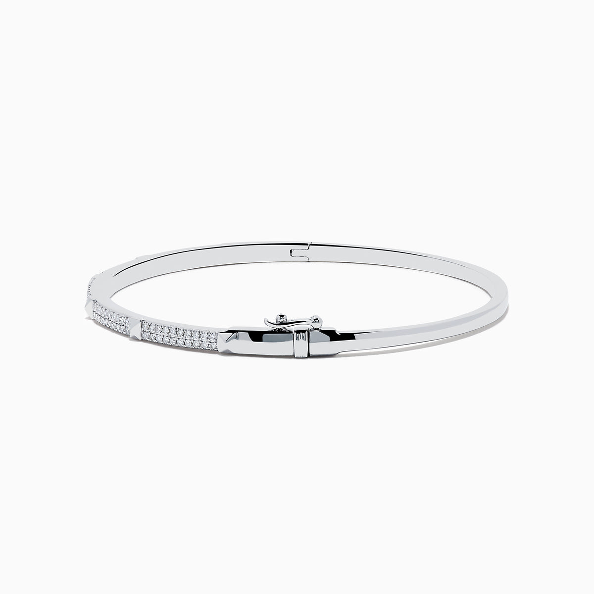 The 14K White Gold Diamond Spike Bangle showcases alternating pyramid studs and rows of sparkling diamonds on its sleek silver surface, set against a plain white background.