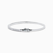 The 14K White Gold Diamond Spike Bangle showcases alternating pyramid studs and rows of sparkling diamonds on its sleek silver surface, set against a plain white background.