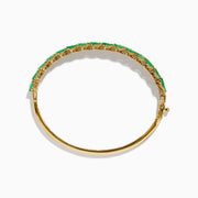 The 14K Yellow Gold Emerald and Diamond Marquise Leaf Bangle showcases an intricate leaf design with alternating emeralds and diamonds set along the band.