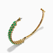 The 14K Yellow Gold Emerald and Diamond Marquise Leaf Bangle showcases an intricate leaf design with alternating emeralds and diamonds set along the band.