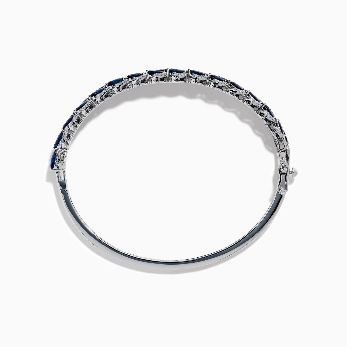 The 14K White Gold Sapphire and Diamond Leaf Motif Bangle features an elegant repeating leaf design with alternating blue sapphires and clear diamonds.