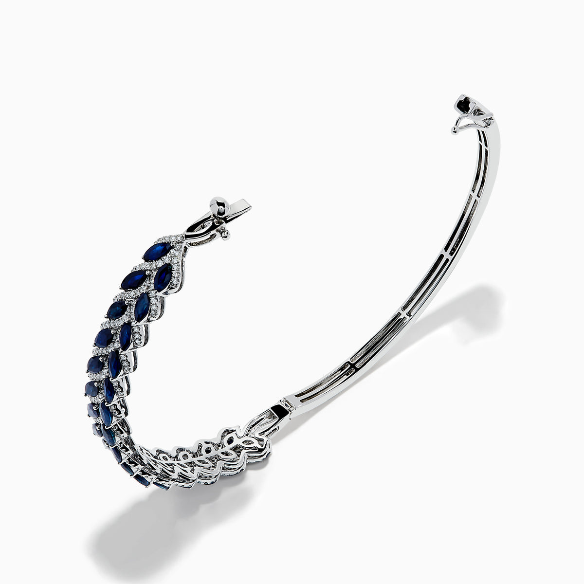 The 14K White Gold Sapphire and Diamond Leaf Motif Bangle features an elegant repeating leaf design with alternating blue sapphires and clear diamonds.