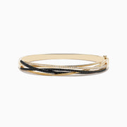 The 14K Yellow Gold Black and White Diamond Crossover Bracelet features overlapping bands adorned with rows of sparkling black and white diamonds, creating an elegant, multi-layered design.