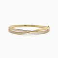 The 14K Yellow Gold Diamond Crossover Ribbon Bangle features overlapping bands in a crossover ribbon style, with some bands encrusted with sparkling diamonds for an elegant, layered look.