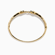 The Signature 14K Gold Diamond and Tsavorite Double Panther Head Bangle features two intertwined bands with geometric black and green enamel, diamond accents, and a panther motif, shown on a white background.