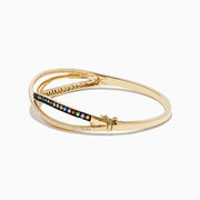 The Watercolors 14K Yellow Gold Multi Sapphire Bangle features crisscrossing bands—one with diamonds, the other adorned with vibrant sapphires—displayed on a white background.