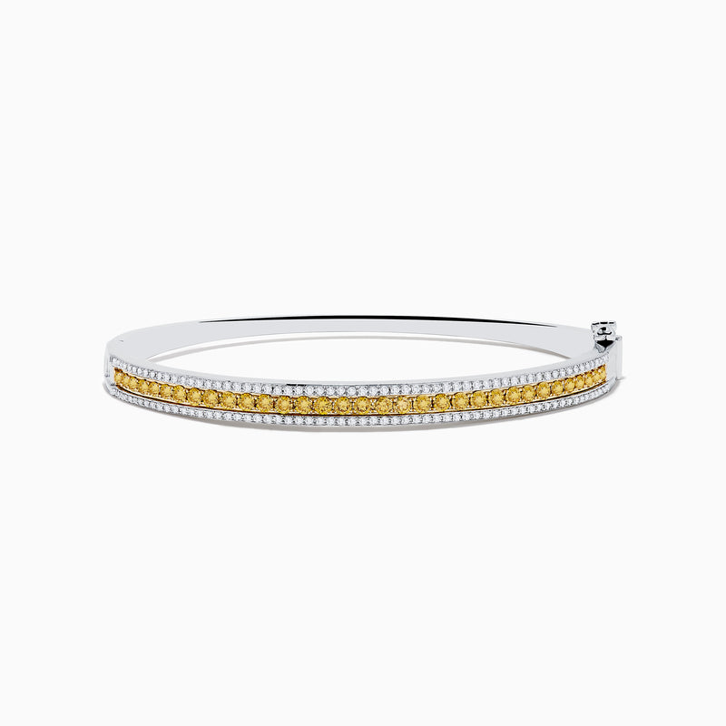 The Canare` 14K Two Tone Yellow and White Diamond Bangle features a central row of yellow diamonds bordered by sparkling white diamonds, all set in a stylish silver bracelet against a clean white background.