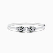 The Signature 14K White Gold Diamond and Tsavorite Bangle showcases two intricate panther heads facing each other, adorned with sparkling diamonds and vibrant tsavorite eyes.