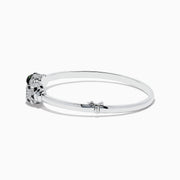 The Signature 14K White Gold Diamond and Tsavorite Bangle showcases two intricate panther heads facing each other, adorned with sparkling diamonds and vibrant tsavorite eyes.
