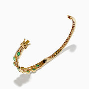 The 14K Yellow Gold Emerald and Diamond Bangle features oval green gemstones, sparkling white diamonds, an elegant openwork design, and a secure clasp.