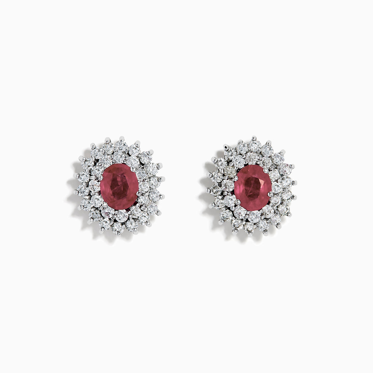 The Ruby Royale 18K White Gold Ruby and Diamond Earrings feature oval red rubies encircled by two halos of sparkling white diamonds, all set in elegant 18K white gold.