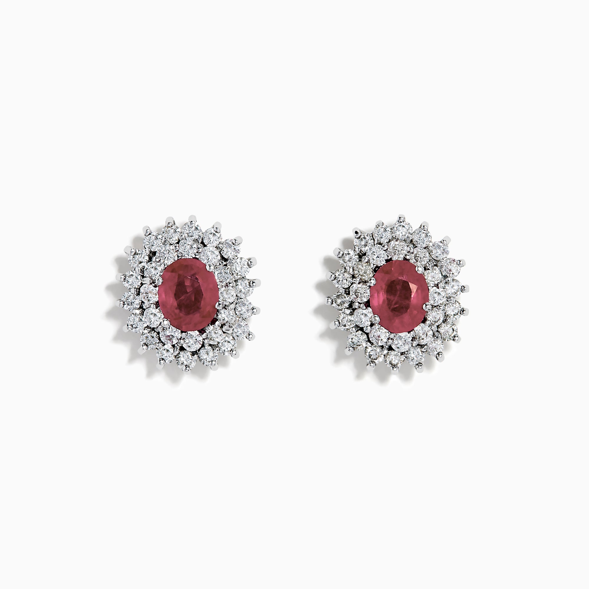 The Ruby Royale 18K White Gold Ruby and Diamond Earrings feature oval red rubies encircled by two halos of sparkling white diamonds, all set in elegant 18K white gold.