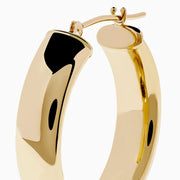 A pair of 14K Yellow Gold Hoops with a smooth, rounded surface shines brightly, displayed vertically against a plain white background.