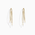 The 14K Yellow Gold Floating Diamond Double Hoop Earrings feature two elongated hoops in yellow gold, each accented with a small floating diamond, and are displayed against a plain white background.