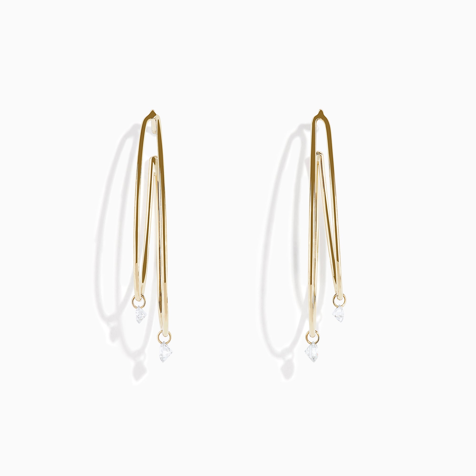 The 14K Yellow Gold Floating Diamond Double Hoop Earrings feature two elongated hoops in yellow gold, each accented with a small floating diamond, and are displayed against a plain white background.