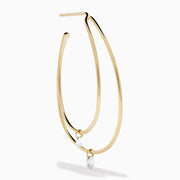 The 14K Yellow Gold Floating Diamond Double Hoop Earrings feature two elongated hoops in yellow gold, each accented with a small floating diamond, and are displayed against a plain white background.