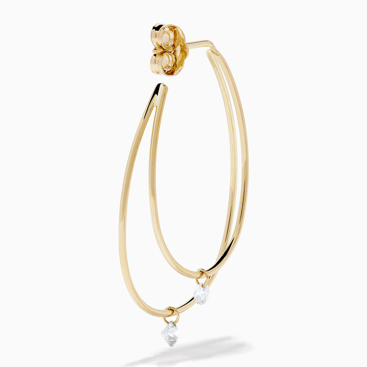 The 14K Yellow Gold Floating Diamond Double Hoop Earrings feature two elongated hoops in yellow gold, each accented with a small floating diamond, and are displayed against a plain white background.