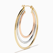 The 14K Three Tone Gold Triple Tube Hoop Earrings are displayed against a white background, with one earring shown front-facing and the other in a side view to highlight the intertwined gold, silver, and rose gold bands.