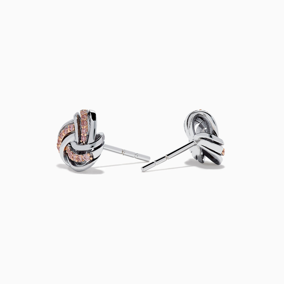 The 14K White Gold Pink Diamond Love Knot Earrings feature an intricate knot design in silver and rose gold tones, accented with sparkling pink diamonds. They are displayed against a plain white background.