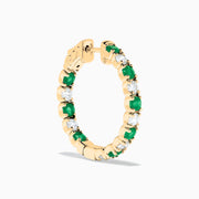 Displayed against a white background, these 14K yellow gold hoop earrings feature alternating emerald and diamond gemstones (3.58 TCW), making for a striking and elegant pair.