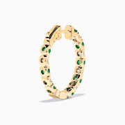 Displayed against a white background, these 14K yellow gold hoop earrings feature alternating emerald and diamond gemstones (3.58 TCW), making for a striking and elegant pair.
