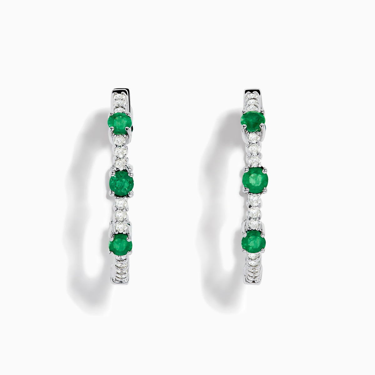 The 14K White Gold Emerald and Diamond Hoops showcase alternating round emeralds and diamonds in silver hoops, displayed against a white background.