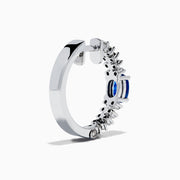 The 14K White Gold Blue Sapphire and Diamond Hoops feature an oval blue sapphire at the center, accented by rows of sparkling diamonds. Displayed on a plain white background.
