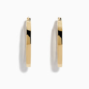 A pair of 14K Yellow Gold Square Tube Oval Hoop Earrings displayed vertically on a white background, casting soft shadows to the right.