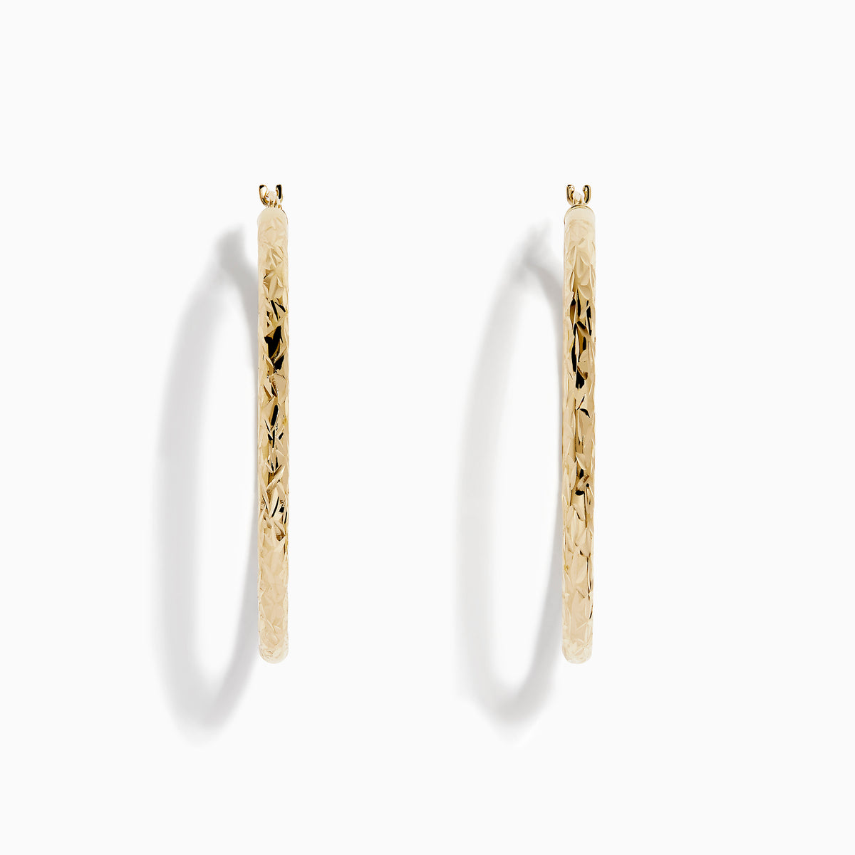 A pair of 14K Yellow Gold Crystal Cut Tube Hoops, large and textured, are displayed vertically on a white background with soft shadows beneath each earring.