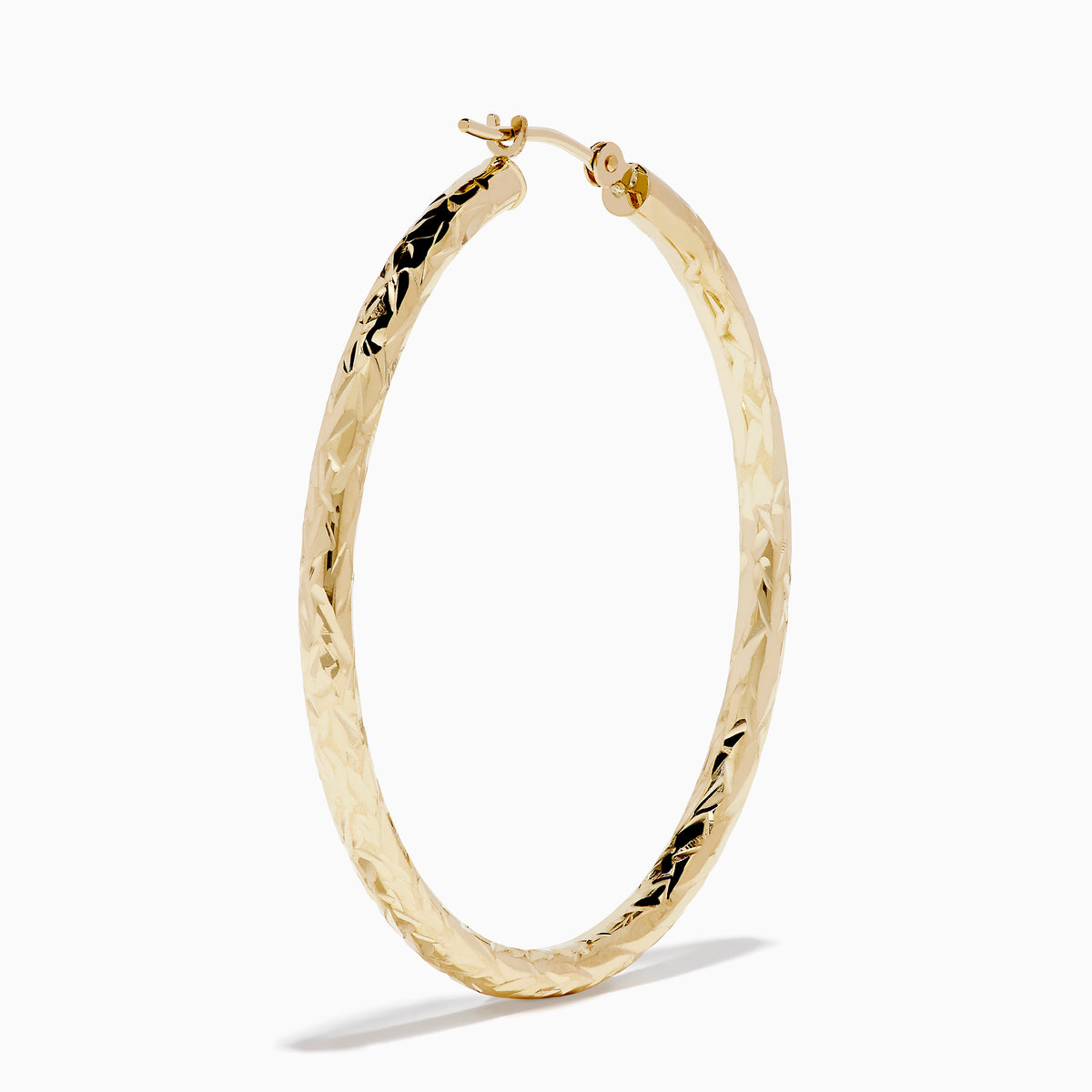 A pair of 14K Yellow Gold Crystal Cut Tube Hoops, large and textured, are displayed vertically on a white background with soft shadows beneath each earring.