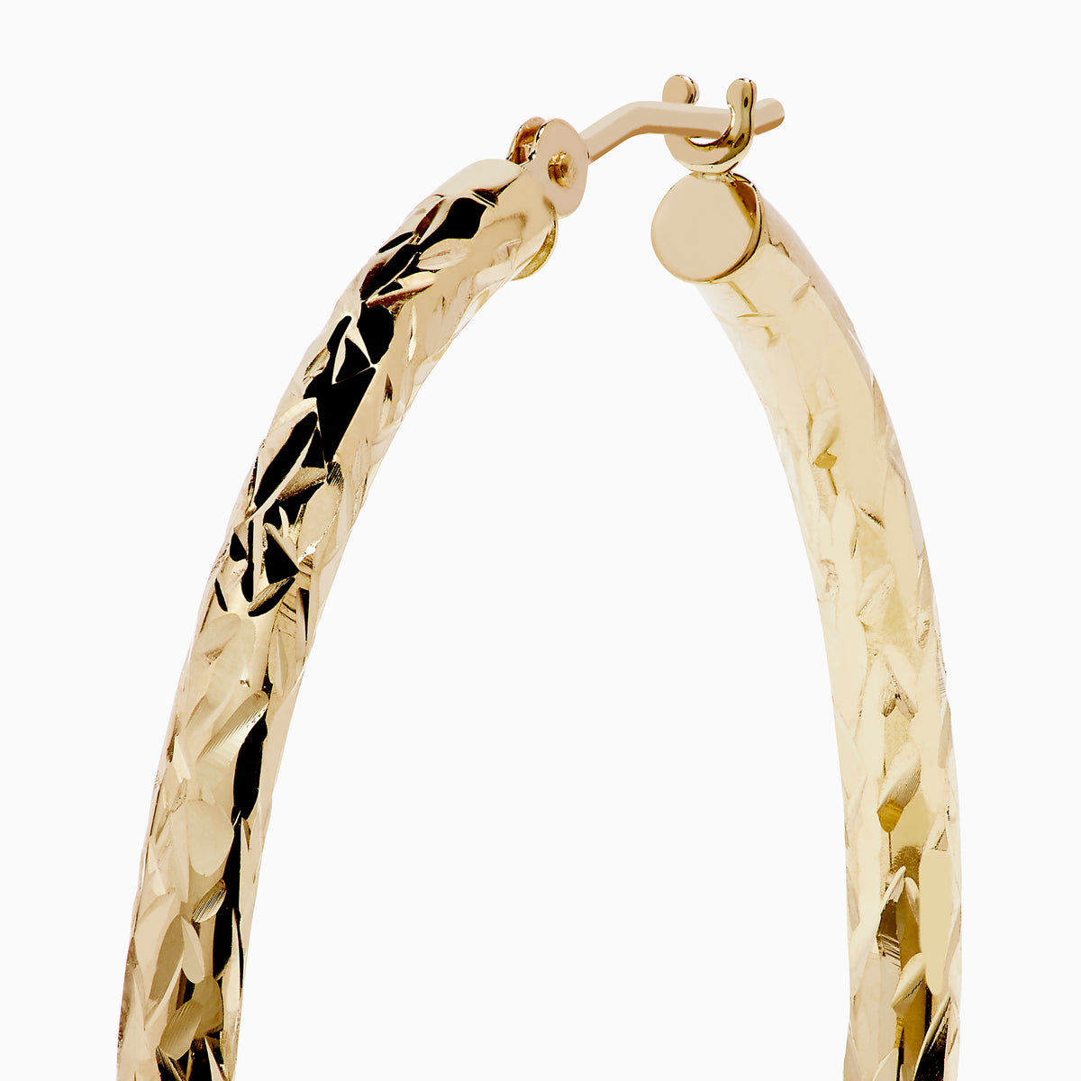 A pair of 14K Yellow Gold Crystal Cut Tube Hoops, large and textured, are displayed vertically on a white background with soft shadows beneath each earring.