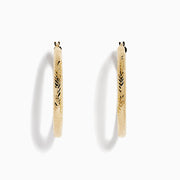 A pair of 14K Yellow Gold Chevron Cut Tube Hoops, displayed against a white background with soft shadows.