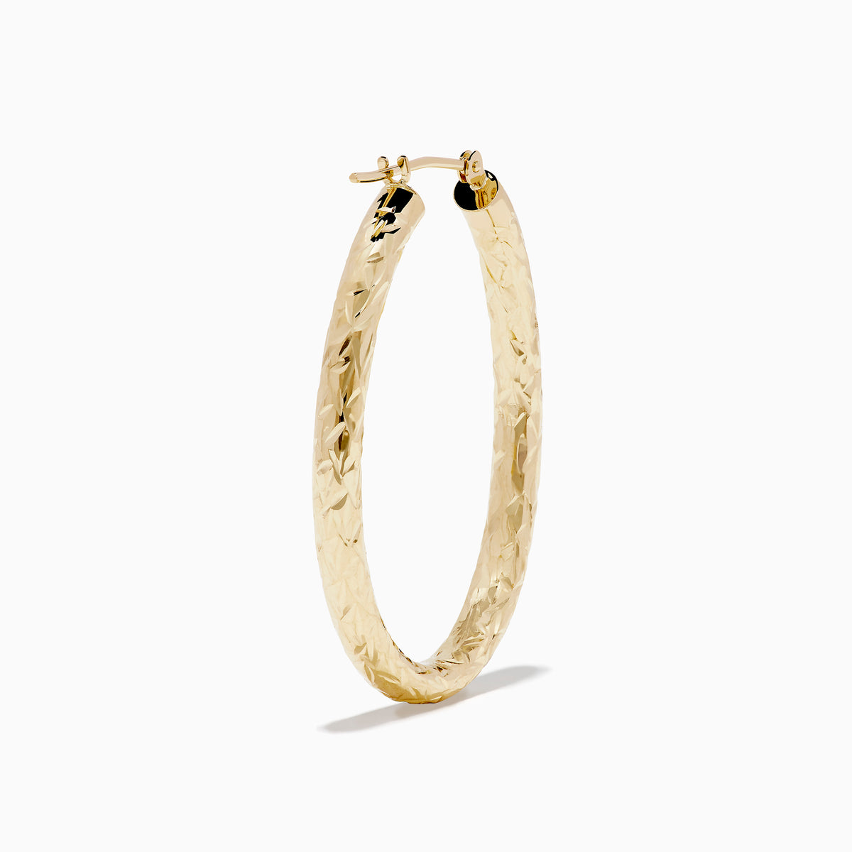 The 14K Yellow Gold Crystal Cut Tube Oval Hoops feature a textured, engraved floral pattern and delicate crystal cut detailing, shown against a plain white background.