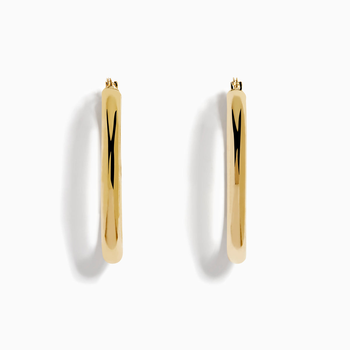 A pair of 14K Yellow Gold Hollow Oval Hoop Earrings displayed vertically on a white background, casting soft shadows to the right.