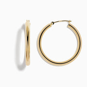 These 14K Yellow Gold Hollow Large Round Hoop Earrings feature a smooth, polished finish and are displayed against a plain white background.