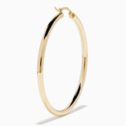 The 14K Yellow Gold Large Tube Hoop Earrings feature a simple, polished design, displayed on a plain white background with subtle shadows.