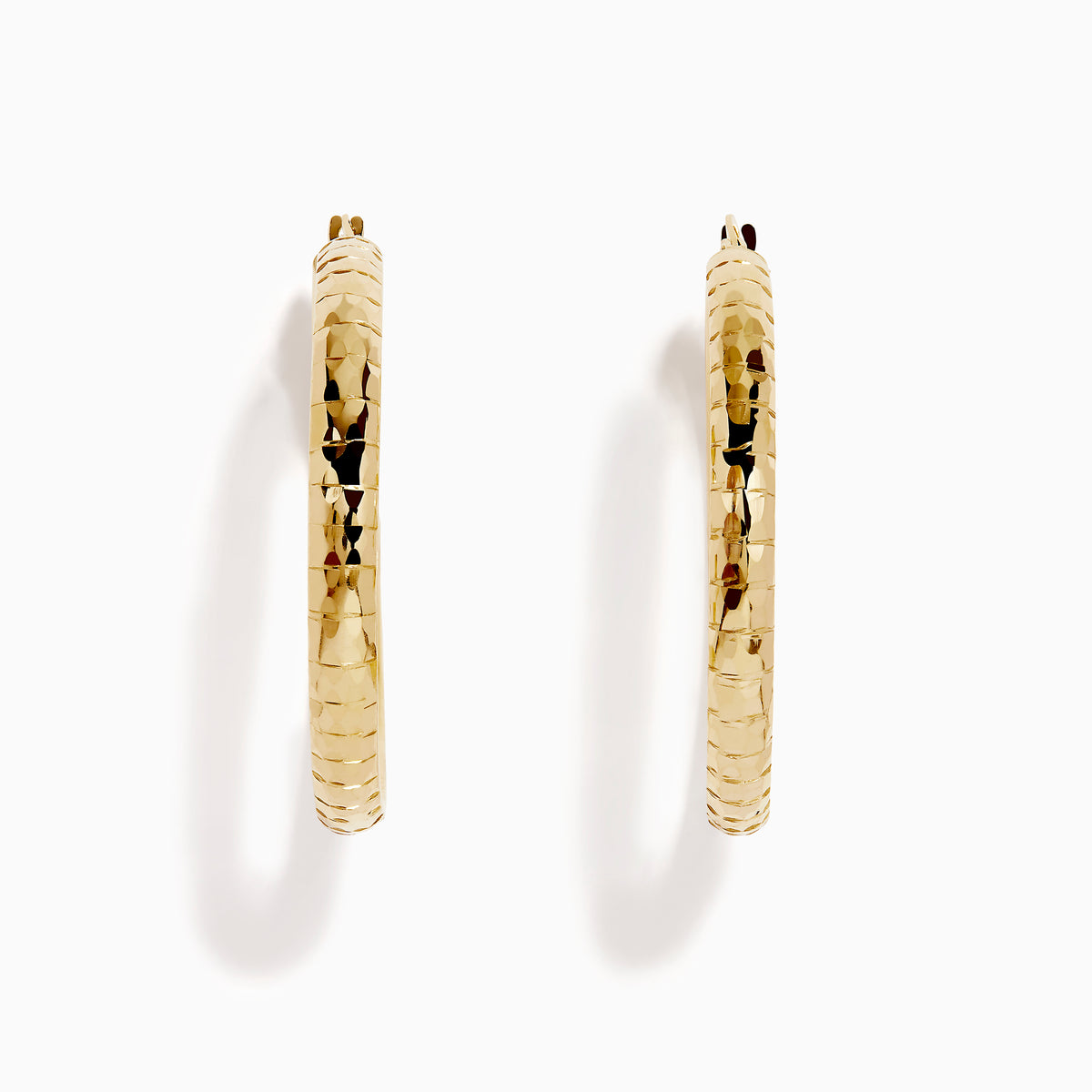 The 14K Yellow Gold Reverse Vibrant Cut Hoop Earrings feature a large, eye-catching design and are showcased against a plain white background with soft shadows.