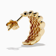The 14K Yellow Gold Croissant Huggie Earrings feature an oval shape with a ridged, twisted design, shown on a white background.