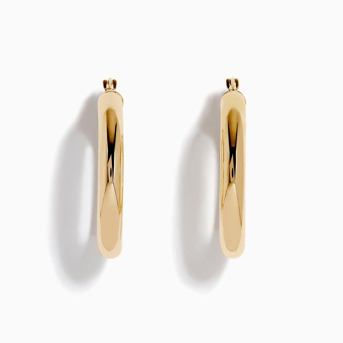 The 14K Yellow Gold Tube Hoop Earrings are shown vertically on a plain white background, with soft shadows cast to the left.