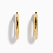 The 14K Yellow Gold Tube Hoop Earrings are shown vertically on a plain white background, with soft shadows cast to the left.