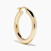 The 14K Yellow Gold Tube Hoop Earrings are shown vertically on a plain white background, with soft shadows cast to the left.