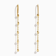 The 14K Yellow Gold Linear Drop Earrings showcase a minimalist design with slim chains and small, spaced gold beads. Crafted in 14K yellow gold, these earrings hang vertically from hooks for a timeless, elegant style.
