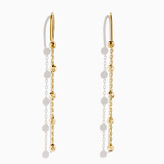 The 14K Yellow Gold Linear Drop Earrings showcase a minimalist design with slim chains and small, spaced gold beads. Crafted in 14K yellow gold, these earrings hang vertically from hooks for a timeless, elegant style.