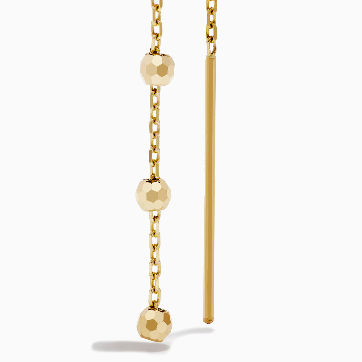 The 14K Yellow Gold Linear Drop Earrings showcase a minimalist design with slim chains and small, spaced gold beads. Crafted in 14K yellow gold, these earrings hang vertically from hooks for a timeless, elegant style.