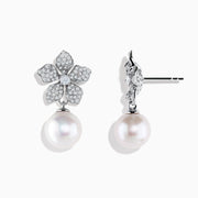 The 14K White Gold Diamond Flower and Fresh Water Pearl Drop Earrings feature diamond-studded flower tops with large round freshwater pearls dangling below, beautifully displayed against a white background.